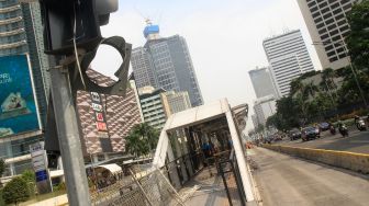 Sejumlah petugas membersihkan puing Halte Bus Trans-Jakarta Tosari yang hangus saat kericuhan unjuk rasa menolak pengesahan Undang-Undang Cipta Kerja di Jalan MH. Thamrin, Jakarta, Jumat (9/10/2020). [Suara.com/Oke Atmaja]