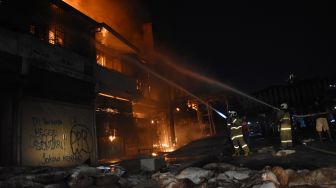 Petugas Pemadam Kebakaran dibantu warga memadamkan api yang menghanguskan bangunan bioskop Grand Theater di kawasan Senen, Jakarta, Kamis (8/10/2020) malam.  [ANTARA FOTO/Indrianto Eko Suwarso]