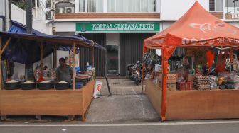 Pedagang menunggu pembeli di depan tenda kios sementara di Pasar Cempaka Putih, Jakarta Pusat, Sabtu (10/10). [Suara.com/Alfian Winanto]