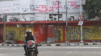 Coretan massa aksi demo tolak Omnibus Law Kamis (8/10) lalu di pertigaan Harmoni yang masih belum dihapus di kawasan Harmoni, Jakarta Pusat, Sabtu (10/10). [Suara.com/Alfian Winanto]