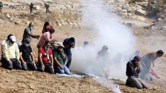 Pengunjuk rasa Palestina berdoa di tengah asap gas air mata yang ditembakkan oleh pasukan keamanan Israel di dekat desa Beit Dajan, Palestina, pada (9/10/2020). [JAAFAR ASHTIYEH / AFP]