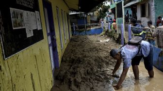 Warga membersihkan lumpur akibar banjir bandang luapan Sungai Cipalebuh, Desa Mandalakasih, Pameungpeuk, Kabupaten Garut, Jawa Barat, Senin (12/10/2020). [ANTARA FOTO/Candra Yanuarsyah]