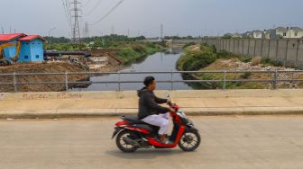 Pengendara motor melintas diatas aliran kali Blencong yang sudah bersih dari sampah di Desa Setia Asih, Kecamatan Tarumajaya, Kabupaten Bekasi, Jawa Barat, Selasa (13/10). [Suara.com/Alfian Winanto]