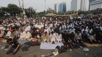 Sejumlah massa dari Persaudaraan Alumni (PA) 212 dan sejumlah ormas Islam melaksanakan Shalat Ashar berjamaah disela-sela menggelar aksi unjuk rasa di kawasan Patung Kuda, Jakarta, Selasa (13/10/2020). [Suara.com/Angga Budhiyanto]