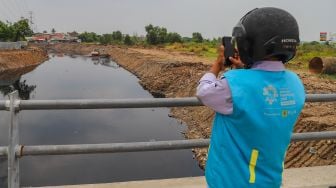 Watga sekitar melihat aliran kali Blencong yang sudah bersih dari sampah di Desa Setia Asih, Kecamatan Tarumajaya, Kabupaten Bekasi, Jawa Barat, Selasa (13/10). [Suara.com/Alfian Winanto]