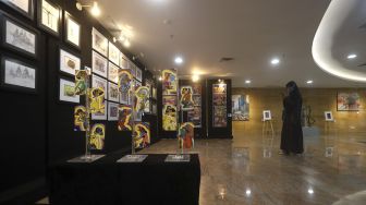 Pengunjung memotret karya seni yang ditampilkan dalam pameran seni rupa bertajuk "Creative Freedom to Heal the Nation (Artists Response to the Pandemic)" di Perpustakaan Nasional, Jakarta, Kamis (15/10/2020). [Suara.com/Angga Budhiyanto]