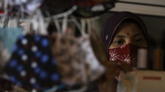 Pekerja memasangkan benang ke mesin jahit saat menyelesaikan pembuatan masker berbahan kain batik di Butik Elemwe, Rawamangun, Jakarta, Jumat (16/10/2020). [Suara.com/Angga Budhiyanto]