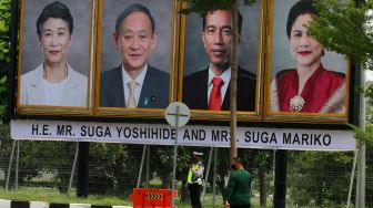 Petugas berjaga dekat foto Presiden Joko Widodo beserta Ibu Negara Iriana Joko Widodo dan Perdana Menteri Jepang Yoshihide Suga bersama Madam Suga Mariko di Bandara Soekarno Hatta, Tangerang, Banten, Selasa (20/10/2020). [ANTARA FOTO]
