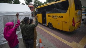 Sejumlah kerabat melambaikan tangan ke arah bus pembawa pasien COVID-19 ke Rumah Sakit Darurat Penanganan COVID-19 Wisma Atlet Kemayoran dari Puskesmas Duren Sawit, Jakarta, Senin (19/10/2020). [ANTARA FOTO/Aditya Pradana Putra]
