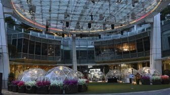 Pengunjung menyantap makanan di dalam instalasi tempat makan berbentuk kubah (dining dome) di Capitol Singapore Outdoor Plaza, Singapura pada (21/10/2020). [ROSLAN RAHMAN / AFP]