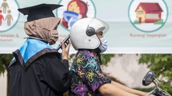 Seorang wisudawan bersama pendamping antre dengan mengendarai sepeda motor untuk mengikuti prosesi wisuda secara "Drive Thru" di Kampus Politeknik Negeri Sriwijaya (Polsri) Palembang, Sumatera Selatan, Sabtu (24/10/2020). [ANTARA FOTO/Nova Wahyudi]