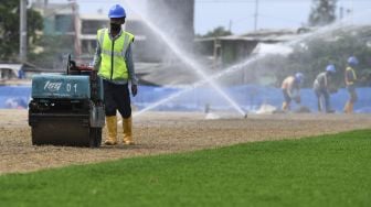 Pekerja menyelesaikan pemasangan rumput untuk lapangan latih di Kompleks Stadion Utama Jakarta International Stadium (JIS), Jakarta, Jumat (23/10/2020). [ANTARA FOTO/Puspa Perwitasari]