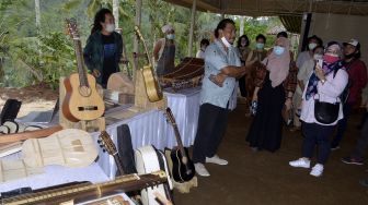 Perajin menjelaskan proses produksi alat musik tradisional buatannya kepada pengunjung kegiatan Lokakarya Produksi dan Distribusi Alat Musik Tradisional di kawasan Desa Sangketan, Tabanan, Bali, Sabtu (24/10/2020). [ANTARA FOTO/Fikri Yusuf]