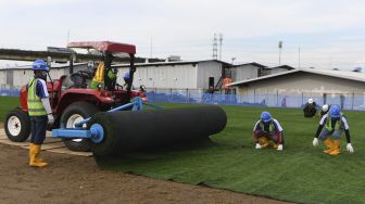 Pekerja menyelesaikan pemasangan rumput untuk lapangan latih di Kompleks Stadion Utama Jakarta International Stadium (JIS), Jakarta, Jumat (23/10/2020). [ANTARA FOTO/Puspa Perwitasari]