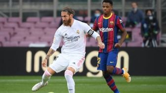 Gelandang Barcelona Ansu Fati (kanan) menantang bek Real Madrid Sergio Ramos selama  pertandingan sepak bola Liga Spanyol antara Barcelona melawan Real Madrid di stadion Camp Nou, Barcelona, Spanyol, Sabtu (24/10). [LLUIS GENE / AFP]

