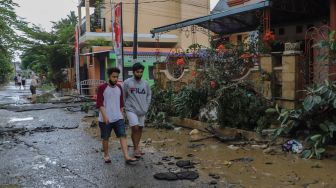 Pohon tumbang dan jalanan rusak juga berlumpur akibat banjir yang melanda di Perumahan Villa Jatirasa, Kota Bekasi, Jawa Barat, Minggu (25/10). [Suara.com/Alfian Winanto]