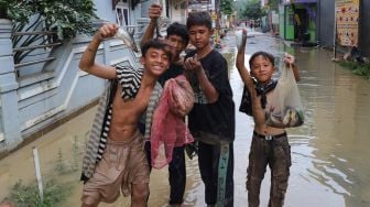 Anak - anak mencari ikan yanh tersapu banjir di Perumahan Villa Jatirasa, Kota Bekasi, Jawa Barat, Minggu (25/10). [Suara.com/Alfian Winanto]