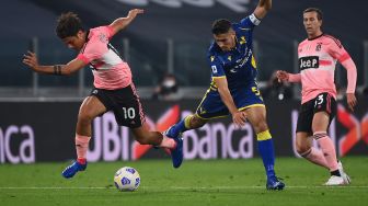 Bek Verona Matteo Lovato memperebutkan bola dengan penyerang Juventus Paulo Dybala bereaksi  selama pertandingan sepak bola Serie A Italia Juventus melawan Verona di Stadion Allianz,Turin, Italia, Senin (26/10) dini hari WIB. [MARCO BERTORELLO / AFP]