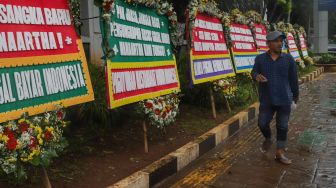 Warga melintasi karangan bunga terkait kasus korupsi Jiwasraya didepan Kejaksaan Agung RI, Jakarta Selatan, Selasa (27/10). [Suara.com/Alfian Winanto]