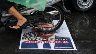 Pengendara melintas di atas poster berwajah presiden Prancis Emmanuel Macron yang ditempel di simpang Jalan Kauman, Yogyakarta, Rabu (28/10/2020).  [ANTARA FOTO/Andreas Fitri Atmoko]