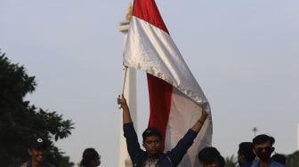 Mahasiswa mengibarkan bendera saat melakukan aksi unjuk rasa di kawasan Patung Kuda Arjuna Wiwaha, Jakarta, Rabu (28/10/2020). [Suara.com/Angga Budhiyanto]