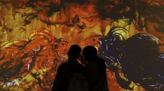 Pengunjung mengamati karya proyeksi video mapping di pameran imersif Affandi: Alam, Ruang, Manusia di Galeri Nasional Indonesia, Jakarta, Jumat (30/10/2020). [Suara.com/Angga Budhiyanto]