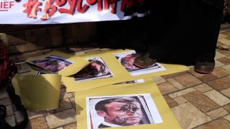 Pengunjuk rasa menginjak poster bergambar Presiden Prancis Emmanuel Macron saat menggelar aksi boikot produk Prancis di Medan, Sumatera Utara, Jumat (30/10/2020). [ANTARA FOTO/Irsan Mulyadi]
