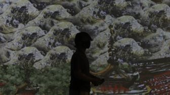 Pengunjung mengamati karya proyeksi video mapping di pameran imersif Affandi: Alam, Ruang, Manusia di Galeri Nasional Indonesia, Jakarta, Jumat (30/10/2020). [Suara.com/Angga Budhiyanto]