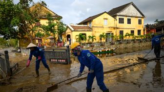 Pekerja kota membersihkan jalan-jalan usai di hantam Topan Molave dan tanah longsor, Vietnam, Jumat (30/10).  [Manan VATSYAYANA / AFP]