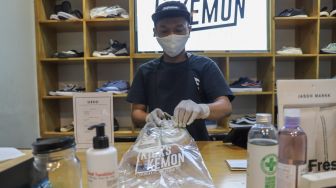 Kru membungkus sepatu pelanggan yang sudah dibersihkan di Cleaning Shoes Kicks Kemon, Haji Nawi, Jakarta Selatan, Minggu (1/11). [Suara.com/Alfian Winanto]