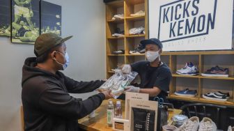 Pelanggan mengambil sepatu yang sudah dibersihkan di Cleaning Shoes Kicks Kemon, Haji Nawi, Jakarta Selatan, Minggu (1/11). [Suara.com/Alfian Winanto]