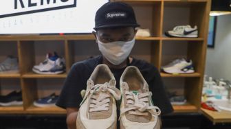 Kru menunjukkan sepatu pelanggan yang sudah dibersihkan di Cleaning Shoes Kicks Kemon, Haji Nawi, Jakarta Selatan, Minggu (1/11). [Suara.com/Alfian Winanto]