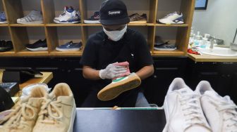 Kru membersihkan sepatu pelanggan di Cleaning Shoes Kicks Kemon, Haji Nawi, Jakarta Selatan, Minggu (1/11). [Suara.com/Alfian Winanto]