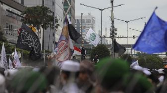 Massa yang tergabung dalam Aliansi Umat Islam mengibarkan benndera saat melakukan aksi unjuk rasa di sekitar Kedubes Prancis, Jakarta, Senin (2/11/2020). [Suara.com/Angga Budhiyanto]