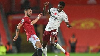 Gelandang Manchester United Bruno Fernandes (kiri) bersaing dengan gelandang Arsenal Thomas Partey (kanan) selama pertandingan sepak bola Liga Inggris antara Manchester United melawan Arsenal di Old Trafford, Manchester, Inggris, Minggu (1/11). [Shaun Botterill / POOL / AFP]