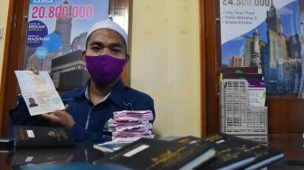 Seorang petugas menunjukan paspor calon jamaah umroh yang tertunda berangkat akibat pandemi COVID-19, saat hari pertama kembali beroperasinya kantor Muhibbah Tour, di Kota Pekanbaru, Riau, Selasa (3/11/2020).  [ANTARA FOTO/FB Anggoro]