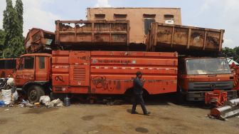 Petugas keamanan berjaga di dekat tumpukan bangkai kendaraan dinas yang sudah tidak layak pakai di Kantor Dinas Lingkungan Hidup DKI Jakarta, Kramat Jati, Jakarta, Rabu (4/11/2020). [Suara.com/Angga Budhiyanto]