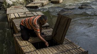 Warga membersihkan sampah yang menyangkut di keramba budidaya ikan di aliran Sungai Cikapundung, Bandung, Jawa Barat, Jumat (6/11/2020). [ANTARA FOTO/Novrian Arbi]