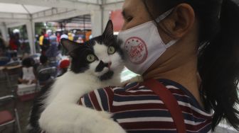 Warga menggendong hewan peliharaannya usai melakukan vaksinasi rabies dan pemeriksaan kesehatan hewan peliharaan secara gratis di Kantor Kelurahan Rawajati, Pancoran, Jakarta, Sabtu (7/11/2020). [Suara.com/Angga Budhiyanto]