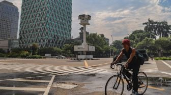 Seorang pesepeda melintas disekitar area Tugu Jam Thamrin di Jl. MH. Thamrin, Jakarta Pusat, Minggu (8/11). [Suara.com/Alfian Winanto]