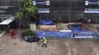 Pekerja melintas di area renovasi gedung Sarinah  di Jalan MH. Thamrin, Jakarta Pusat, Minggu (8/11). [Suara.com/Alfian Winanto]