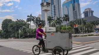 Pedagang melintas disekitar area Tugu Jam Thamrin di Jl. MH. Thamrin, Jakarta Pusat, Minggu (8/11). [Suara.com/Alfian Winanto]