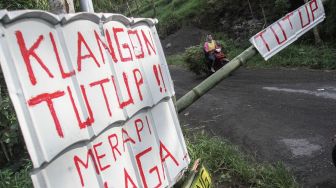 Warga membawa rumput melintas di palang pintu wisata alam Bukit Klangon di Desa Glagaharjo, Cangkringan, Sleman, DI Yogyakarta, Minggu (8/11/2020). [ANTARA FOTO/Hendra Nurdiyansyah]