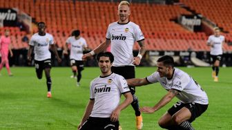 Gelandang  Valencia Carlos Soler (tengah) merayakan golnya bersama rekan satu timnya setelah mencetak gol ke gawang Real Madrid selama pertandingan sepak bola Liga Spanyol antara Valencia melawan Real Madrid di Stadion Mestalla, Valencia, Spanyol, Senin (9/11) dini hari WIB.  [JOSE JORDAN / AFP]