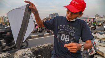 Seorang warga memasang tali di layangannya untuk bermain di samping Fly Over Kalibata, Jakarta Selatan, Senin (9/11). [Suara.com/Alfian Winanto]