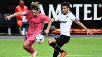 Gelandang Real Madrid Luka Modric berduel dengan bek Valencia Jose Luis Gaya Pena (kanan) selama pertandingan sepak bola Liga Spanyol antara Valencia melawan Real Madrid di Stadion Mestalla, Valencia, Spanyol, Senin (9/11) dini hari WIB. [JOSE JORDAN / AFP]