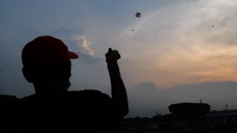 Seorang warga menerbangkan layangannya di samping Fly Over Kalibata, Jakarta Selatan, Senin (9/11). [Suara.com/Alfian Winanto]