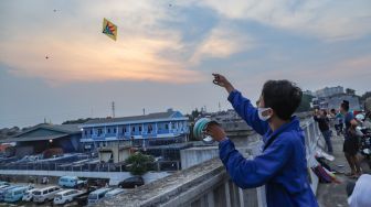 Seorang warga menerbangkan layangannya di samping Fly Over Kalibata, Jakarta Selatan, Senin (9/11). [Suara.com/Alfian Winanto]