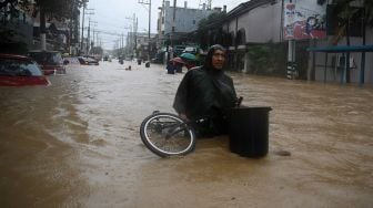 Warga membawa sepeda saat menerobos banjir akibat Topan Vamco,  di Manila, Filipina, Kamis (12/11/2020).  [Ted ALJIBE / AFP]