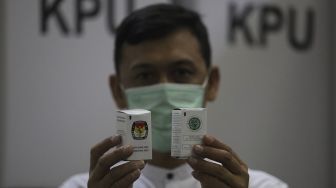 Petugas menunjukkan tinta di Gudang Logistik KPU, Depok, Jawa Barat, Jumat (13/11/2020). [Suara.com/Angga Budhiyanto]